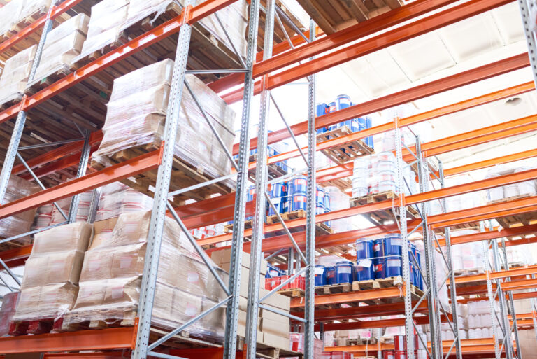 Wide angle view at tall storage shelves with packed goods in warehouse, background with copy space